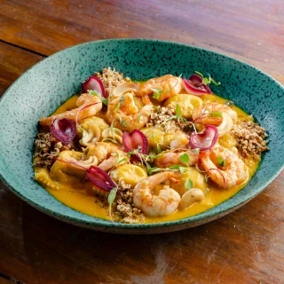 <p>Raviloli de Vatapá com molho de moqueca, camarão grelhado e maturi. Acompanha farofa de licuri</p>