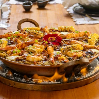 <p>Baião do Amor - Blend de feijões verdes, arroz pilaf, mix de cogumelos frescos, fumeiro artesanal e queijo coalho. Finalizado com camarões gigantes, bacon crocante e  milho assado na brasa.</p>