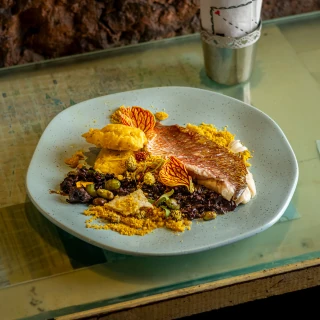 <p>Peixe confitado com arroz negro, ao molho de moqueca</p>