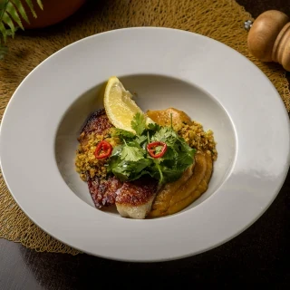 <p>Peixe do dia grelhado. Acompanha pur&ecirc; de banana frita e leite de coco, lim&atilde;o cravo e pangrattato de p&atilde;o de alho.</p>