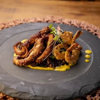 Arroz negro com castanhas, camarões, polvo grelhado e molho de açafrão