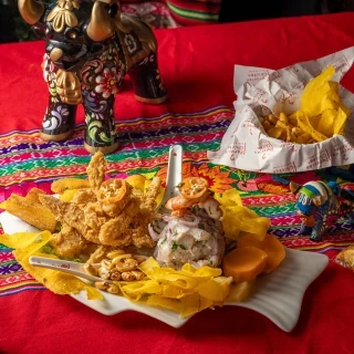 DUO PERUVIAN - Ceviche Mixto e Chicharrón de Pescado: Peixe e Frutos do Mar marinados na tradicional leche de tigre peruano, acompanhado de peixe crocante por fora, macios e suculentos por dentro, com milho e chifles peruanos.